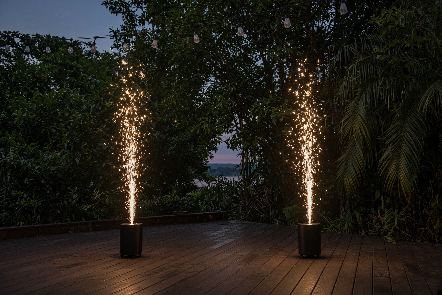 Cold spark fountains rising from a wooden deck at dusk.